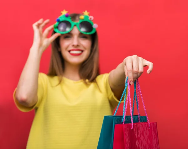 Žena s vánoční večírek brýle a nákupní tašky — Stock fotografie