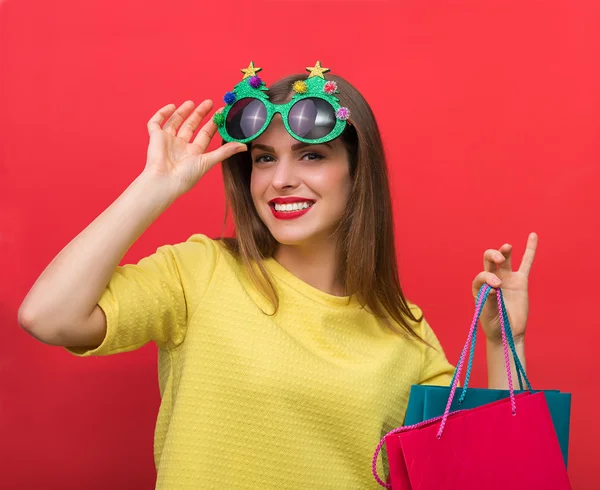 Kvinna med Christmas party glasögon och påsar — Stockfoto