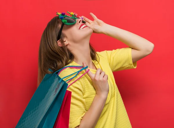 Woman with Christmas party glasses and shopping bags — Stock Photo, Image