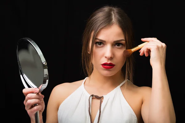 Woman with a mirror and makeup brush