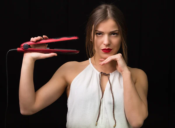 Mulher com um ferro de cabelo liso — Fotografia de Stock