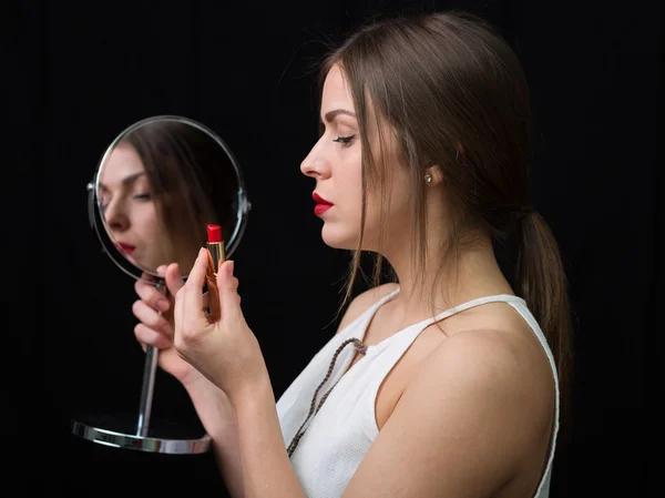 Vrouw met een spiegel en een rode lippenstift — Stockfoto