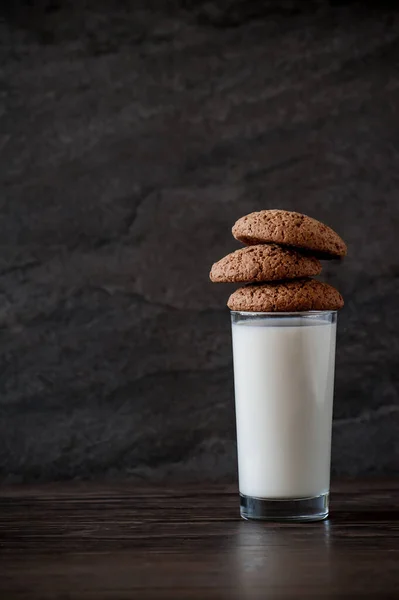 Glass of milk and oatmeal cookies on a wooden table — Stock Photo, Image