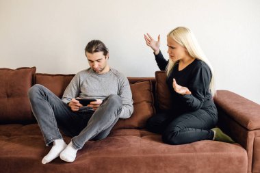 Karısı onu sözlü olarak korkuturken elinde akıllı telefon olan bir adam. Agresif kadın kocasının moralini bozmuyor. İlişki Krizi Konsepti