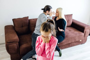 Mutsuz küçük bir kız çocuğu yüzünü kapatıyor, gürültülü aile tartışmasından muzdarip, öfkeli anne ve baba bağırıyor ve kavga ediyor, aile çatışması, çocuklar ve boşanma.