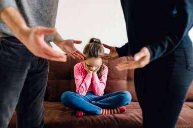 Çocuk kızı, anne ve babasının tartışmasının neden olduğu psikolojik sorunlar yüzünden üzgün, küçük bir kız çocuğu arka planda kavga ederken üzgün hisseder.,