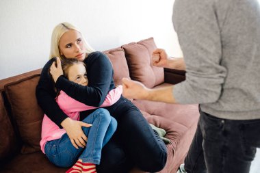 Evde şiddet - agresif bir adam karısına ve kızına sözlü saldırıda bulundu. Aile içi şiddet ve istismar mağduru kadın ve çocuk. Koca, karısını ve kızını korkutur..