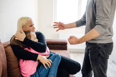 Evde şiddet - agresif bir adam karısına ve kızına sözlü saldırıda bulundu. Aile içi şiddet ve istismar mağduru kadın ve çocuk. Koca, karısını ve kızını korkutur..