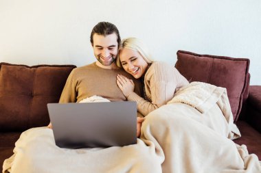 Komedyen filmi izleyen, gülümseyen genç sarışın kadın ya da evde sevgili kocasıyla bilgisayardaki komik videolar.