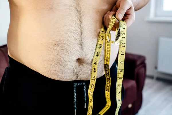 close up of a belly fat man  with measurement tape.  Problem with overweight, bad health and dieting concept