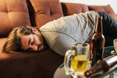 Genç adam yeni yıl partisinden sonra akşamdan kalma, kanepede kaosla uyuyor. Parti bittiği zaman. Genç yakışıklı adam partiden sonra dağınık odada kanepede sızdı.