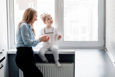 Anneler Günü, anneler günü. Anne ve kızı evdeki pencerenin yanında birlikte oynuyorlar. Ebeveynlik ve annelik Neşe Konsepti
