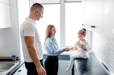 Aile, anne, baba ve küçük kızları hakkında günlük sahneler. Çocuğu beslemek. Çocuk yemek istemiyor.
