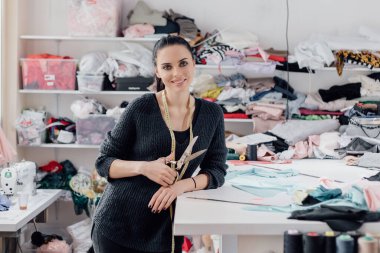 Kadını terzi yapar. Ölçü bandı olan terzi, arka planda makas atölyesi tutuyor. Profesyonel terzi ya da tasarımcı. Terzi dükkanı.. 