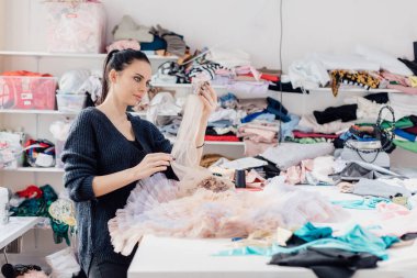 İç çamaşırı dikme işlemi. Kumaş imalatında terzi. Atölyedeki kadın terzinin portresi, kadın terzi. Evde rahat bir odada giysi yap..