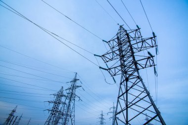 Mavi gökyüzü arka planında elektrik direkleri. Güç ve enerji. Enerji korunumu. Enerji endüstrisi, enerji tasarrufu