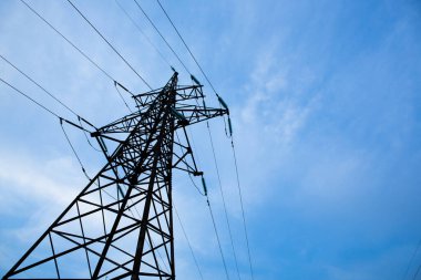 Mavi gökyüzü arka planında elektrik direkleri. Dağıtım istasyonunda kablo kablosu olan yüksek voltaj şebekesi kulesi. Enerji endüstrisi, enerji tasarrufu