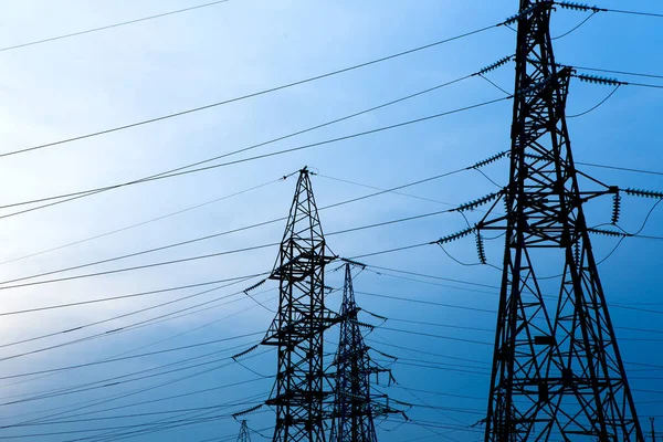 Mavi gökyüzü arka planında elektrik direkleri. Dağıtım istasyonunda kablo kablosu olan yüksek voltaj şebekesi kulesi. Enerji endüstrisi, enerji tasarrufu