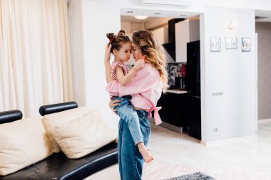 İki insanın portresi. Sevimli anne ve küçük kızı sarılıyor. Annesine sarılıyor. Evde, oturma odasında. Annelik, bekar annelik.