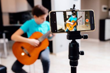 Kafkasyalı ergen çocuk evdeki müzik dersinde gitar ve plak çalıyor. Online müzik dersleri. Hobi, müzik, sanat ve yaratılış kavramı. seçici odak