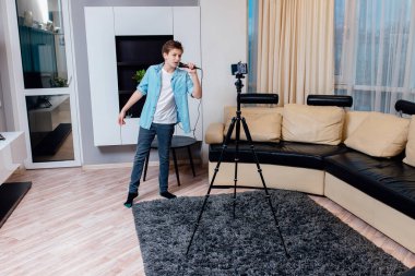 Çocuk blogcu canlı yayın yapıyor. Genç mikrofona şarkı söylüyor. Ergenlik çağındaki blog yazarı akıllı telefon kullanarak müzik yapıyor. Bloglama, müzik, yaratım.