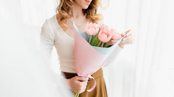 Young woman at home mother\'s day concept holding tulips bouquet smiling close up. beautiful woman smelling bouquet of tulips at home