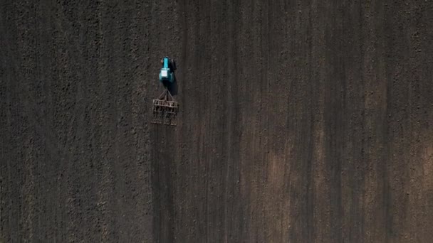 Bovenaanzicht van een trekker met eggen systeem ploeggrond op landbouwgrond, — Stockvideo