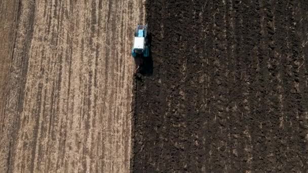 Aerial view of a tractor plowing dry agricultural field, — стоковое видео