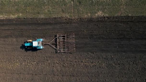 Aerial top view of one tractor dragging a disc harrow or a seedbed cultivator — Stockvideo