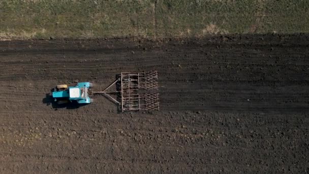 Aerial top view of one tractor dragging a disc harrow or a seedbed cultivator — стоковое видео