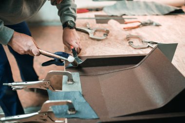 Bir işçinin elini kapat. Metal levhayı kesmek için makas kullan.