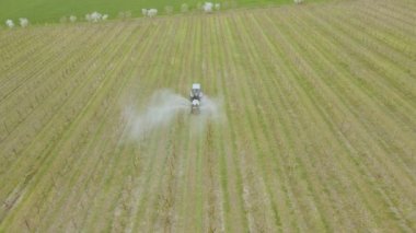 4K 'da bir traktörün çiftçilere elma mahsulü püskürttüğü hava görüntüsü..