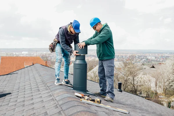 İki profesyonel usta Roofer inşaat işçileri bacayı tamir ediyorlar.
