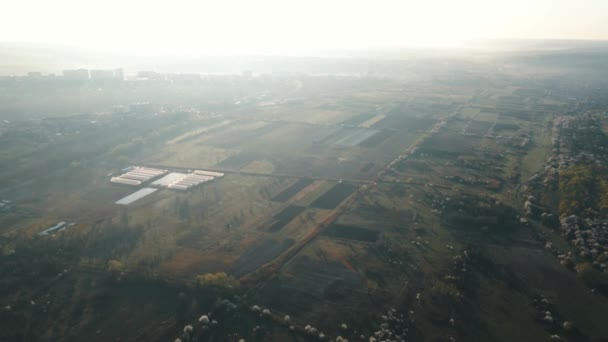 Вид з повітря на сільськогосподарські поля біля передмістя міста вранці на сході сонця . — стокове відео
