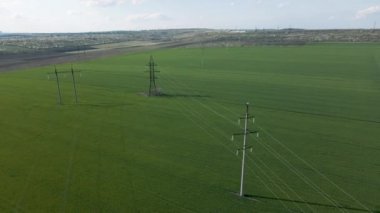 Düz ve yeşil bir alanda yüksek voltaj hatları ve güç direklerinin havadan görüntüsü