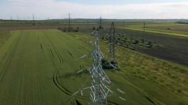 İnsansız hava aracı tarım arazisi üzerinde uçuyor ve güzel gökyüzüne karşı yüksek voltajlı elektrik pilonu.