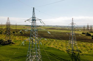 İnsansız hava aracı tarım arazisi üzerinde uçuyor ve güzel gökyüzüne karşı yüksek voltajlı elektrik pilonu..