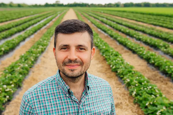 young bearded farmer of European nationality looks at the camera and smiles.