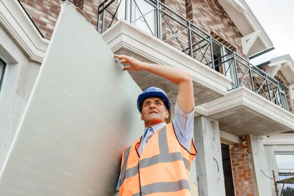 Portrait of confident indian male construction worker at construction site hold in hands cardboard Drywall.