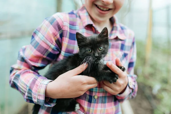 Крупним планом Щаслива дитина грає з чорним кошеням . — стокове фото