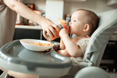 Kadın anne çocuğuna su şişesi verir..