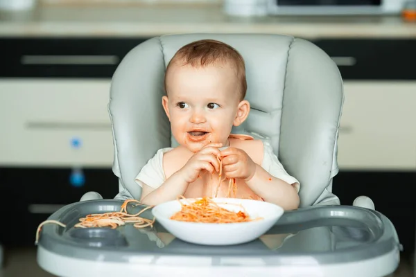 Scena domestica con un bambino piccolo ragazzo mangiare spaghetti. — Foto Stock