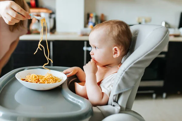 Mano della madre che porge gli spaghetti al bambino — Foto Stock