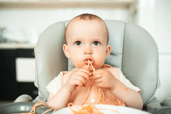 Dolce bambino ragazzo fare un pasticcio in cucina mentre mangiare spaghetti — Foto Stock