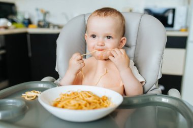 Küçük bebek spagetti yiyor ve etrafı kirletiyor.