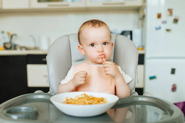 Piccolo bambino mangiare spaghetti cena e fare un pasticcio — Foto Stock
