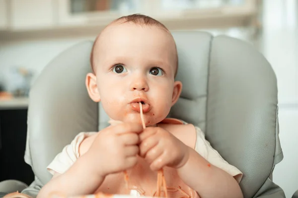 Dolce bambino ragazzo fare un pasticcio in cucina mentre mangiare spaghetti — Foto Stock