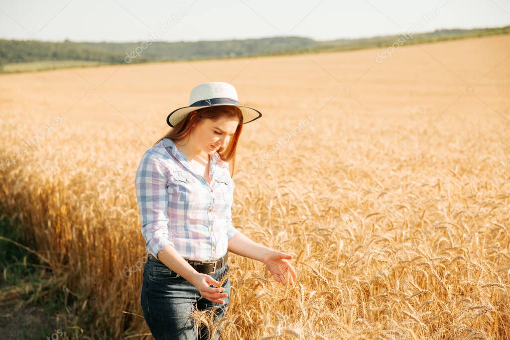 A woman farmer with hat, plant specialist, analyzing the field wheat