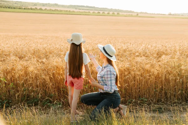 Bakifrån av mor och dotter pekar på vetefält. — Stockfoto