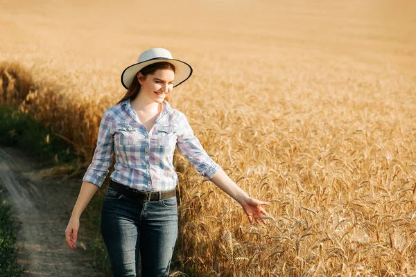 agronomist woman with hat studying wheat harvest in the field.